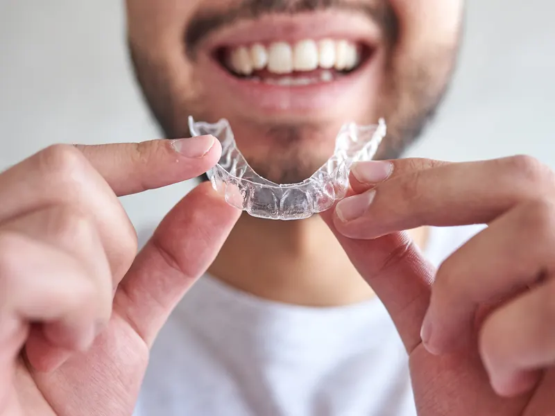 Hombre sonriendo con un alineador transparente en las manos